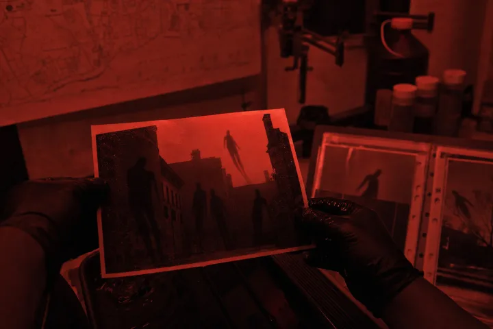 Stampe fotografiche in una camera oscura con cinque ombre impossibili sulla carta