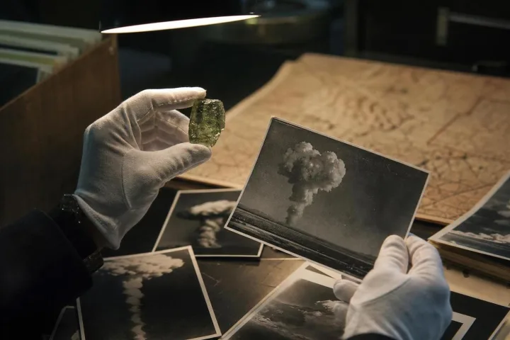Fotografie d’archivio e un frammento di trinitite esaminati sotto una lampada